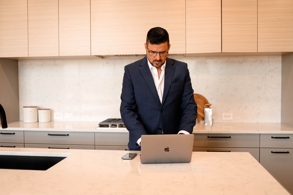Ezra Malo, Calgary REALTOR® at RE/MAX First, reviewing recent home sales on his laptop at a kitchen island